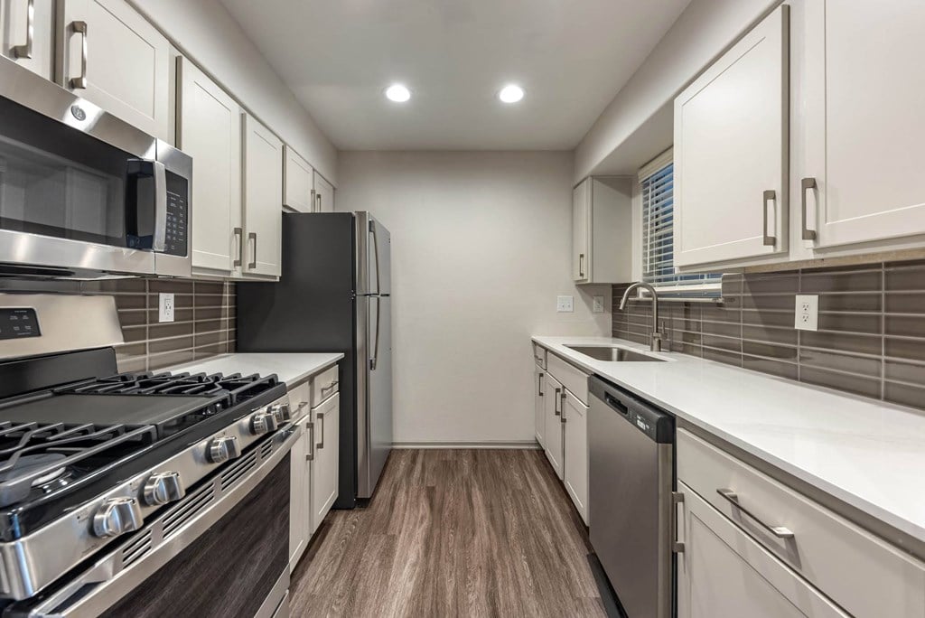 a modern kitchen with stainless steel appliances and white cabinets